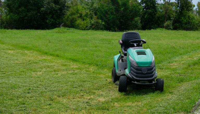 Green Riding Mower Cutting Grass at Public Park