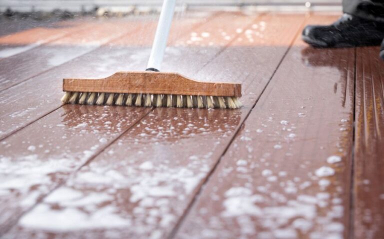Man Using a Scrub Brush to Clean a Deck With Soap