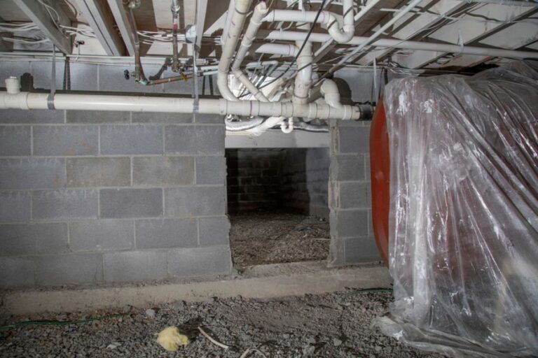 Cinder Block Crawl Space With Visible Plumbing and Oil Tank