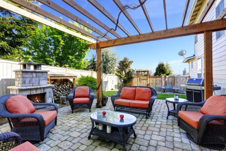 Wicker Furniture and a Fireplace Covered by a Pergola in a Backyard