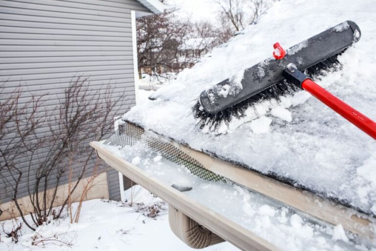 Man Attempting to Clear Snow and an Ice Dam With a Broom