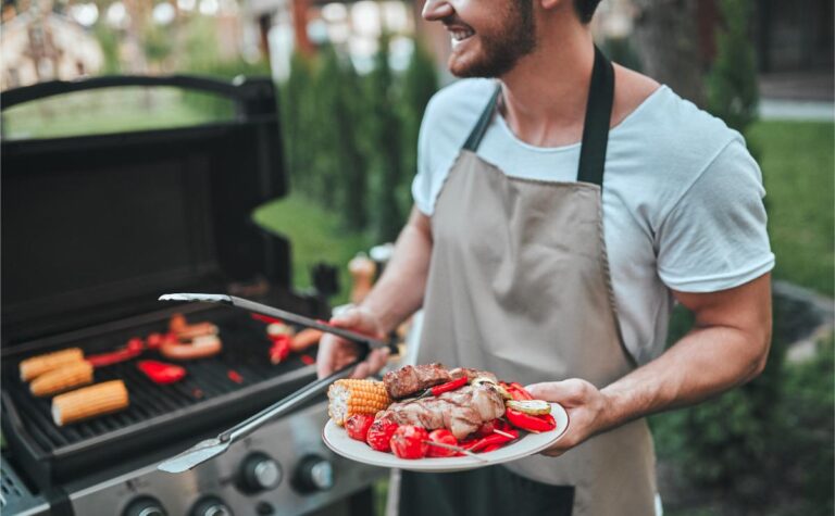 Man Grilling and Smiling While Holding Plate of Food