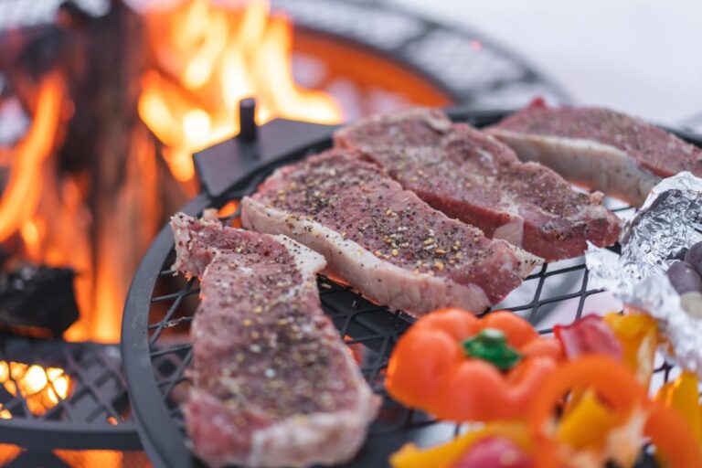 Cooking Steak and Vegetables on a Black Grate Over a Fire Pit