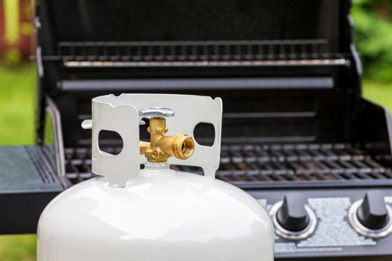 A propane tank in front of a grill